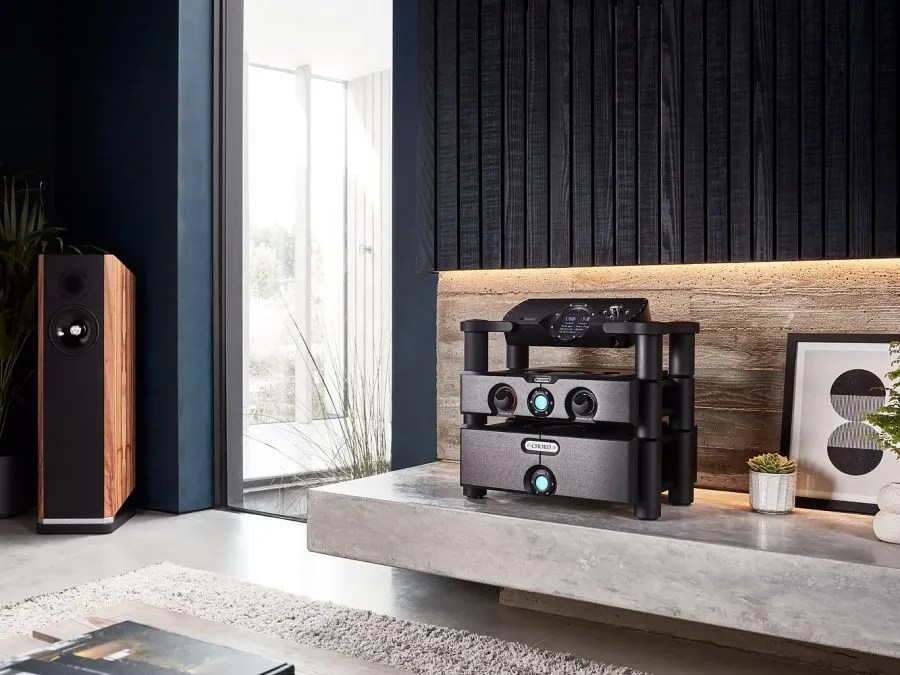 The same three-box Choral system in black, on black Ensemble stands against a dark timber wall