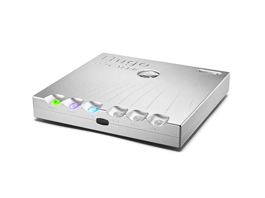 The silver Hugo M Scaler in three-quarter view from the left, showing how shallow the chassis is, the dimpled arcs across the lid and the three lit spheres along the front edge